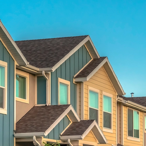 Beige and blue townhomes with a sunny sky in the background