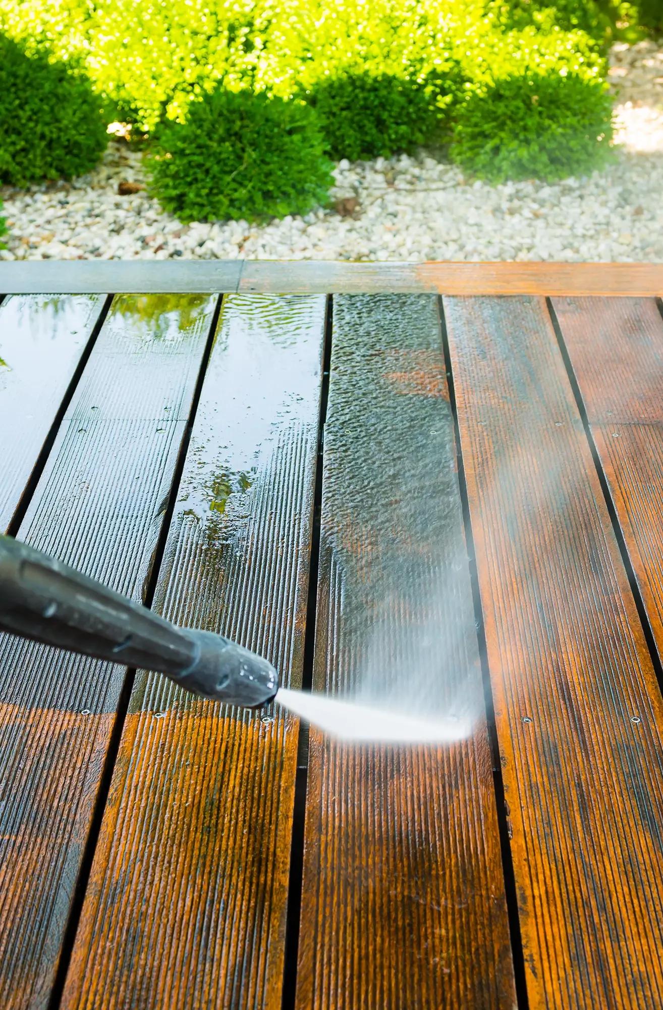A person is power washing a wooden deck