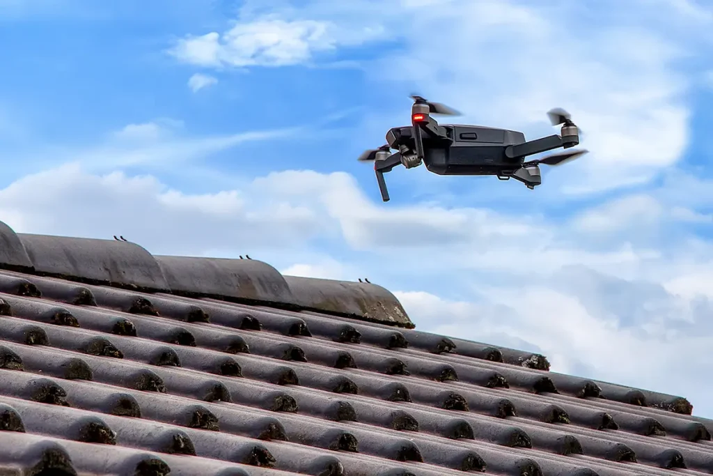 Drone in the air inspecting the roof over the house.