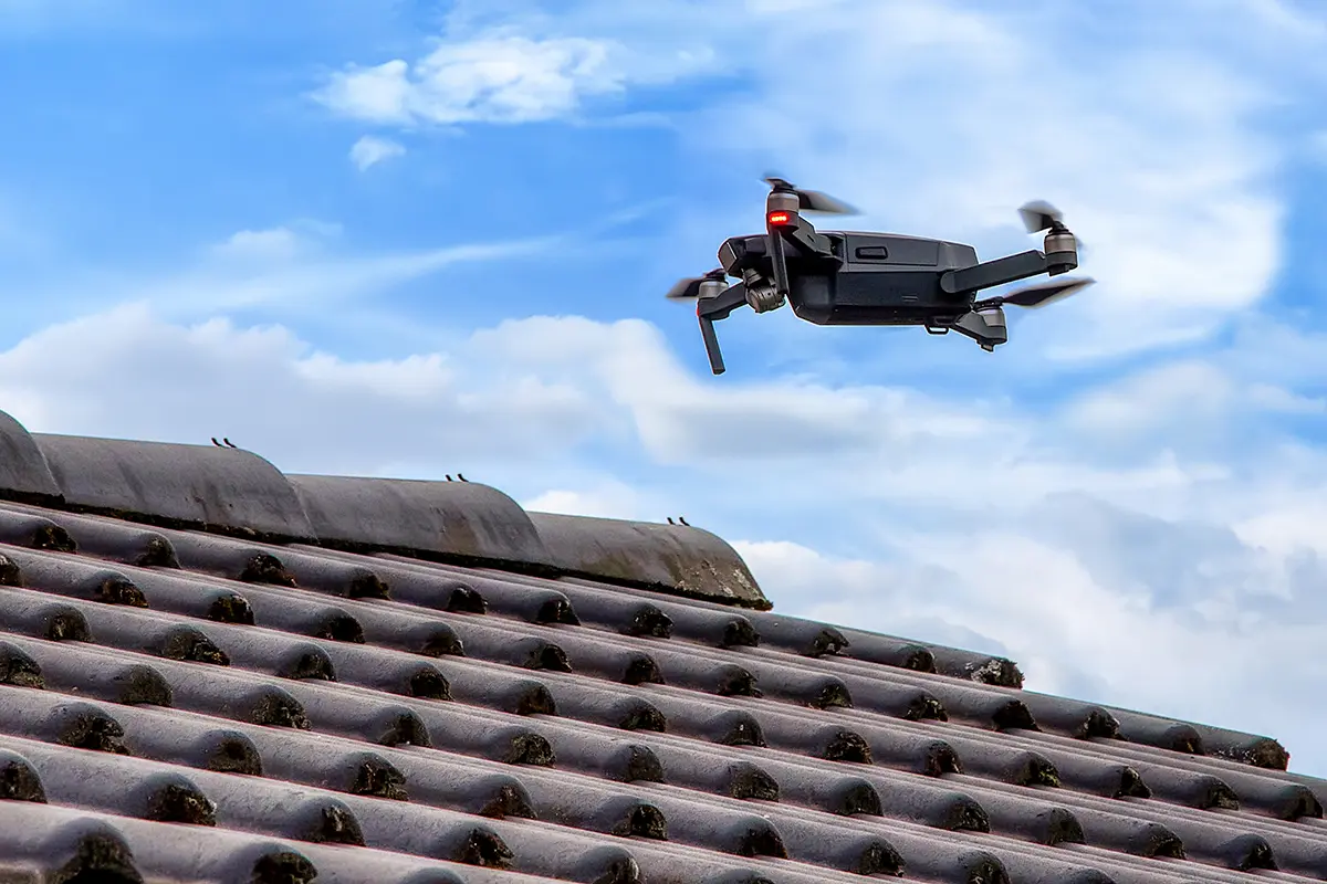 Drone in the air inspecting the roof over the house.