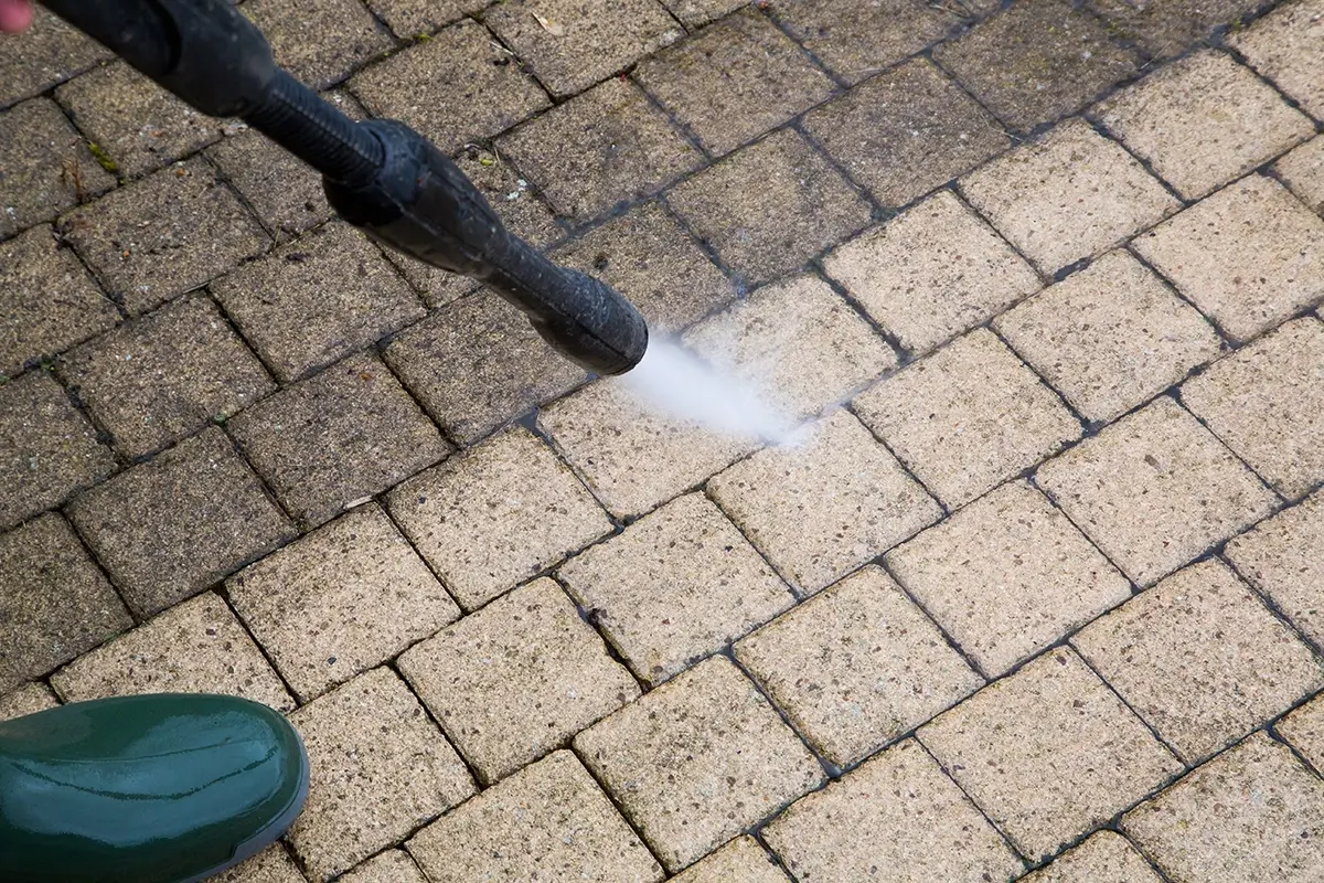 Pressure washer cleaning a outdoor pathway thats half cleaned,